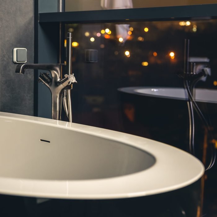 The interior of a modern bathroom with a window overlooking the night city, copy space.